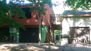 Ein zweistöckiges Gebäude mit einer grünen Garagentür, einer Treppe, die zu einer oberen Ebene führt, und einem kleinen Vorbereich.