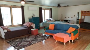 Ein gemütliches Wohnzimmer mit einer Couch, einem Hocker und einem Bett.
