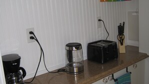A kitchen with a coffee maker, toaster, and a knife block on the counter.