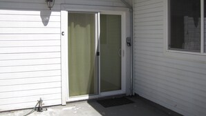 A white house with a sliding glass door, a window, and a small outdoor light fixture.