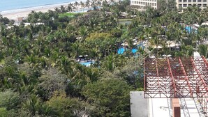 Un resort con piscina, palmeras y vistas a la playa y al océano.