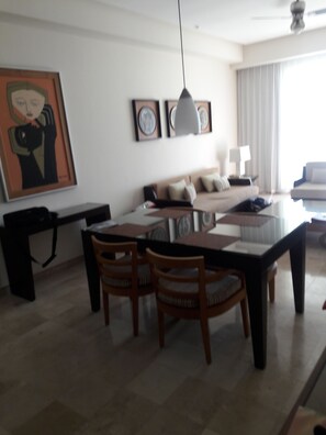 Un salon moderne avec un coin repas, comprenant un ensemble de canapés, une table à manger avec des chaises et un ventilateur de plafond.