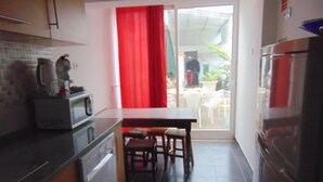 A compact kitchen with a microwave, a sink, and a refrigerator. There is a dining area with a table and chairs. - Rio ... Beaches ... Lisbon, Ideal for families with children and pets. (Almada)