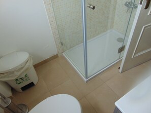 A bathroom with a toilet, a glass-enclosed shower, and a trash bin. - Rio ... Beaches ... Lisbon, Ideal for families with children and pets. (Almada)