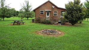 A wooden cabin with a fire pit in the yard, surrounded by trees and a picnic table. - Morningstar Cabin Caddo River. GREAT VALUE!!!!!!!!!!! River access!! (Glenwood)