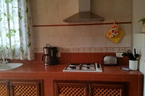 Una cocina con estufa a gas, cafetera, tostadora y pileta.