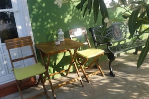 A wooden table and chairs set against a green wall, with a metal bench and a white lantern on the table. - Apartment Clary in Gomera with Unique Views, Close to Beach (Vallehermoso)