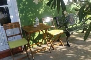 A wooden table and chairs set against a green wall, with a metal bench and a white lantern on the table. - Apartment Clary in Gomera with Unique Views, Close to Beach (Vallehermoso)