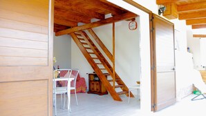 A wooden interior with a staircase leading to an upper level, a white chair, and a small table with a bottle. - Comfortable to the Sea, House (Contrada Fiori Sud)