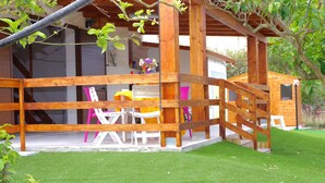 A wooden cabin with a covered porch, a small play area, and a dining table with chairs. - Comfortable to the Sea, House (Contrada Fiori Sud)