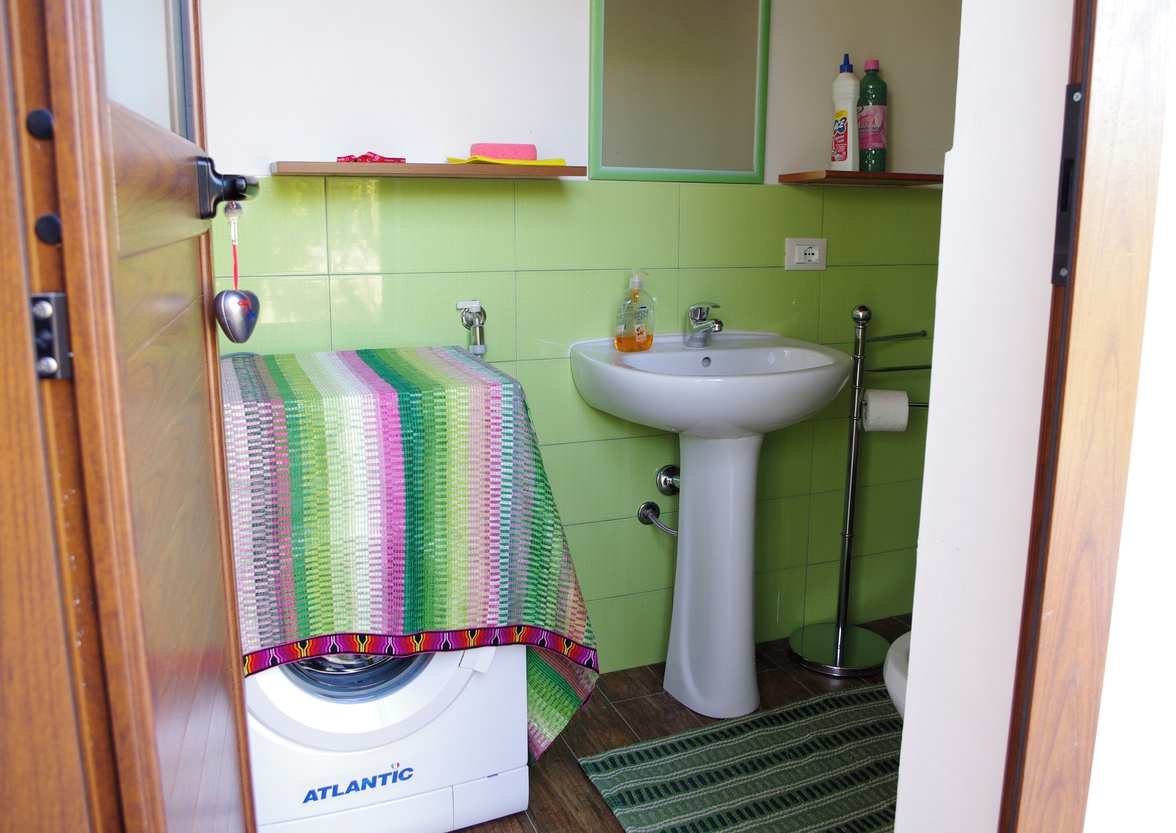 Un baño pequeño con lavadora, lavamanos y espejo.
