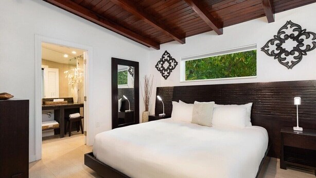 A bedroom with a large bed, a desk, and a mirror.
