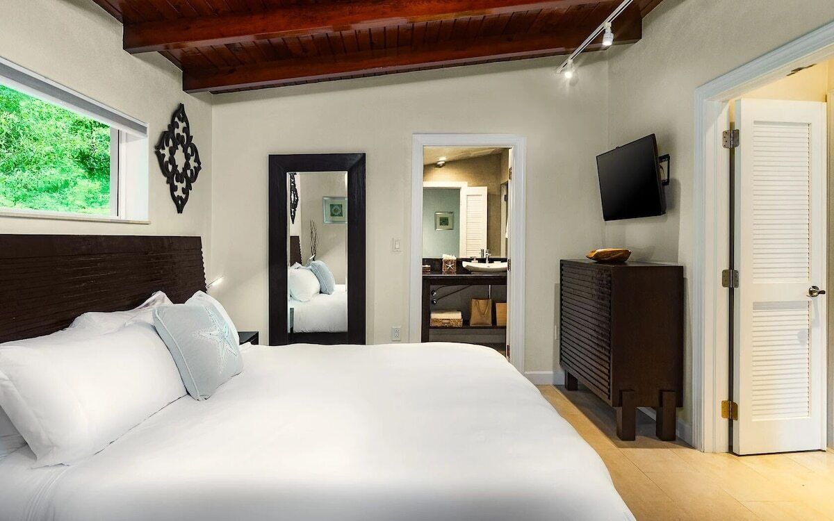 Un dormitorio con una cama grande, un espejo, un televisor y un armario.