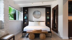 A bedroom with a large bed, a wooden bench, and a circular artwork on the wall.