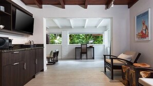 A modern kitchen with dark wood cabinets, a flat-screen TV, and a dining area with a table and chairs.