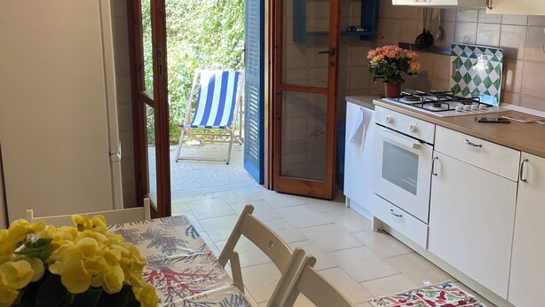 A kitchen with a dining table, chairs, a gas stove, cabinets, and a view of the outside. - Blue house 500m from the beach of Porto Cesareo (Porto Cesareo)
