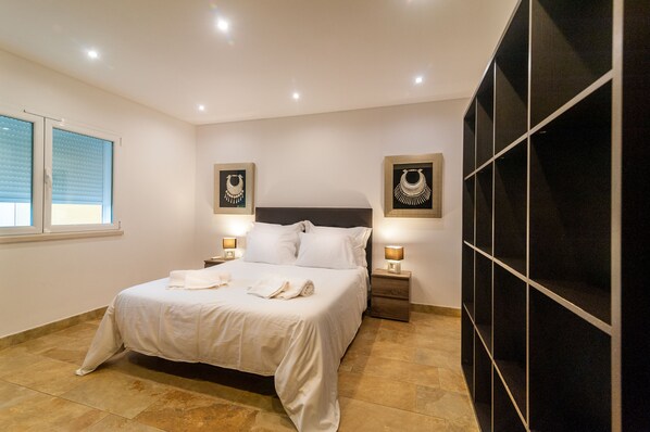 A neatly arranged bedroom with a bed, two bedside tables with lamps, and a large wardrobe.