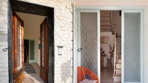 A hallway with a wooden door, a red chair, and a staircase leading to an upper floor. - Foscolo 1, 100m from the beach (Viareggio)