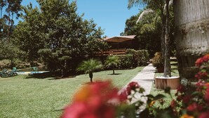 Un jardín bien cuidado con un sendero, una terraza de madera y un edificio al fondo.
