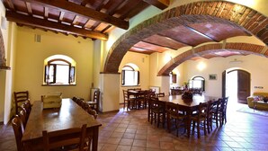A spacious dining area with high wooden ceilings and brick arches, featuring multiple wooden tables and chairs. - AGRITURISMO LA PIETRAIA (Poppi)
