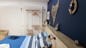 A neatly made bed with striped bedding, a wooden headboard, and a wall-mounted shelf with decorative items. - Between the sea and the Eternal City, Guest room ''Sottocoperta'' (Roma)