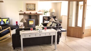 Una sala de estar acogedora con chimenea, un sofá, una mesita de centro y un televisor.