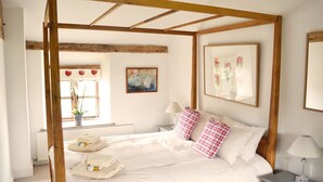 Un dormitorio con cama con dosel, una ventana con vistas a flores y un cuadro en la pared.