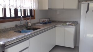 Una cocina con gabinetes blancos, encimera de granito, un fregadero y un refrigerador.