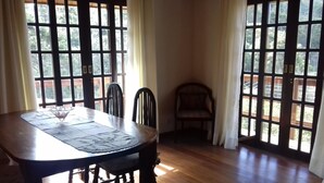 Un comedor con mesa de madera, sillas y ventana con vistas a árboles.