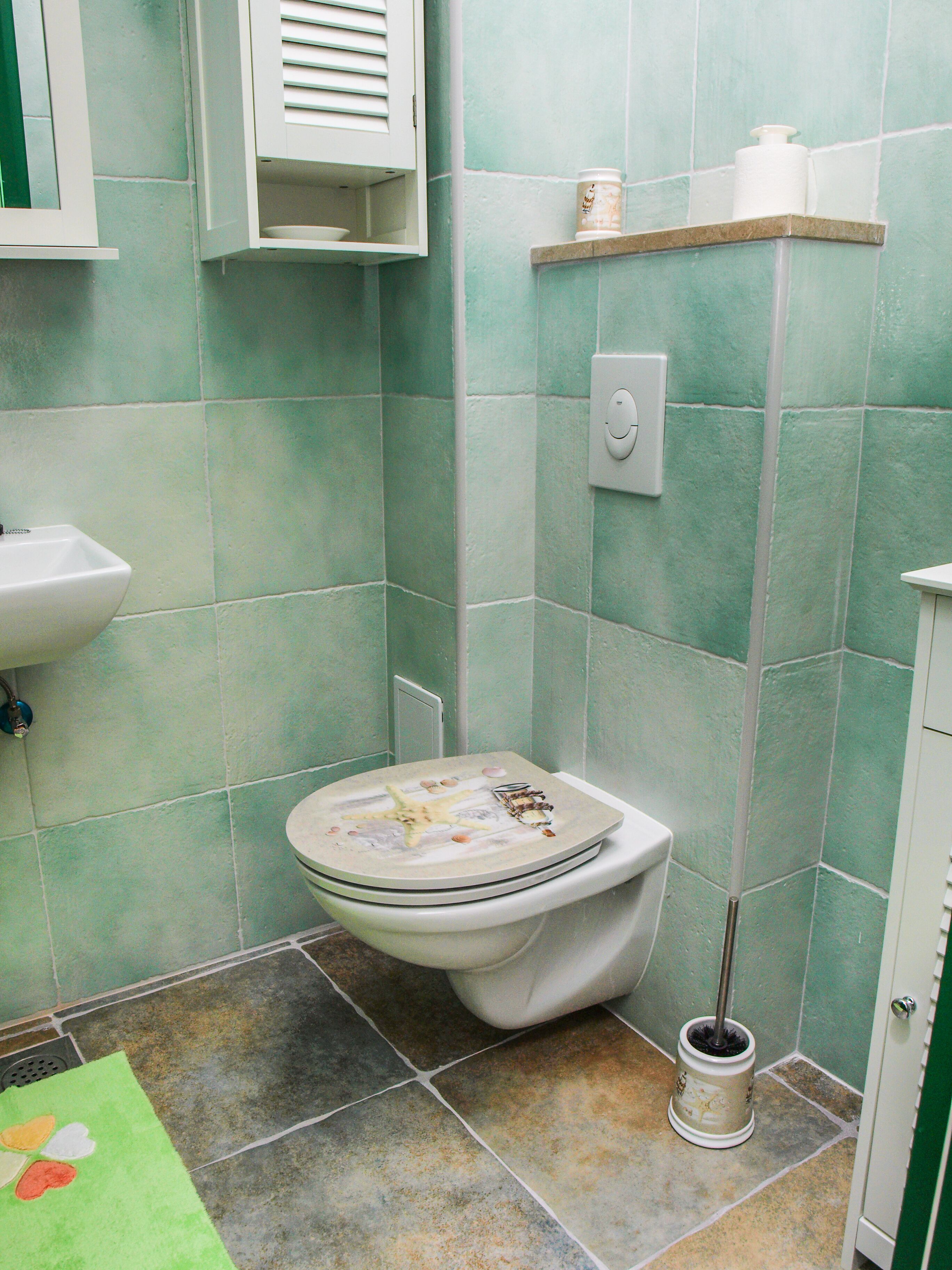 A bathroom with a toilet, sink, and shower area.