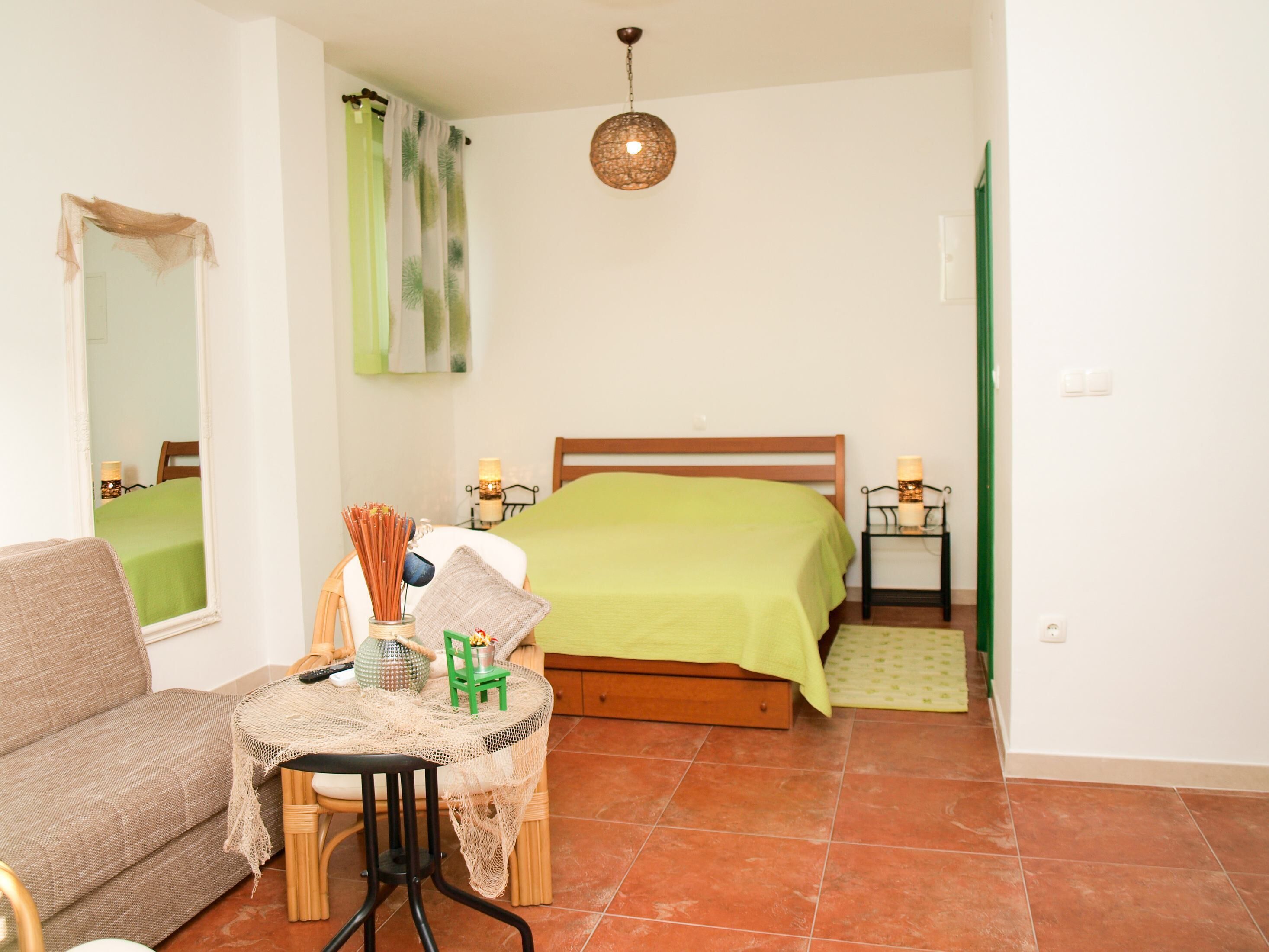 Une chambre à coucher avec un lit, une table et une chaise, un miroir et un luminaire suspendu.