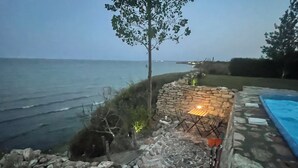 Un patio de piedra con mesa y sillas, una piscina y vistas al océano.