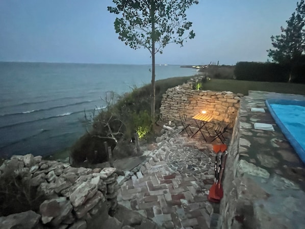 Een terras van natuursteen met een tafel en stoelen, een zwembad en uitzicht op de oceaan.