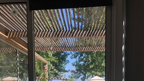 Una habitación con un amplio ventanal que da a una terraza exterior con una hamaca, un trípode y una tienda de campaña.