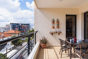 A balcony with a view of the city, potted plants, and outdoor furniture.