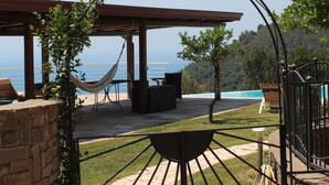Un patio con una hamaca, mobiliario exterior y vistas al mar.