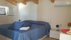 Un dormitorio con cama, mesita de noche, escritorio y equipo de aire acondicionado.