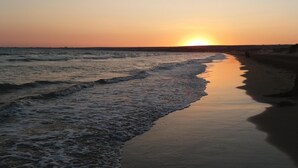 Una playa al atardecer, con olas suaves lamiendo la orilla.
