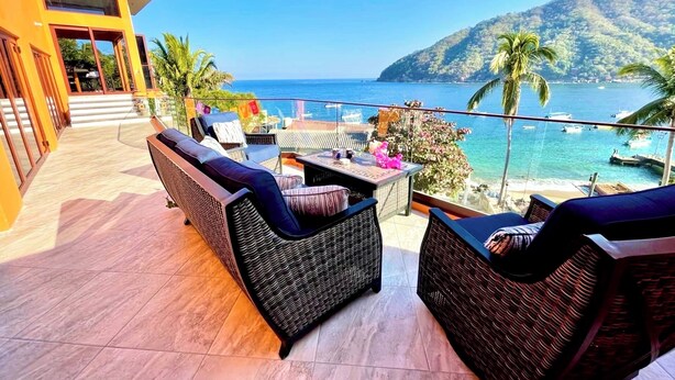 A balcony with wicker furniture, a view of the sea, and a mountain in the background. - Penthouse in Yelapa, Brand New and Luxurious Casa, Sleeps 8 very comfortably (Yelapa)