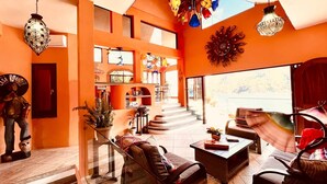 A spacious living area with a sofa, coffee table, and decorative items on a table. - Penthouse in Yelapa, Brand New and Luxurious Casa, Sleeps 8 very comfortably (Yelapa)