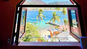A room with a view of a beach, palm trees, and boats. - Penthouse in Yelapa, Brand New and Luxurious Casa, Sleeps 8 very comfortably (Yelapa)