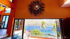 A room with a view of the sea, a sun-shaped wall decoration, and a staircase leading to an outdoor area. - Penthouse in Yelapa, Brand New and Luxurious Casa, Sleeps 8 very comfortably (Yelapa)