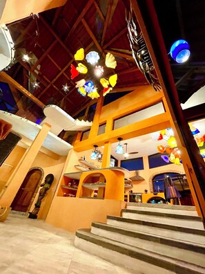 A multi-level interior with a staircase, wooden beams, and hanging decorative lights.