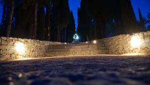 A stone staircase leading up to a lighted entrance in a forested area. - Our apartment is located at quiet area, with big terrace and nice garden arround (Korčula)