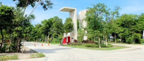 A modern building with a unique architectural design, surrounded by lush greenery and a paved pathway.