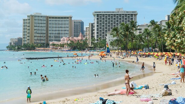 A beach with people swimming and sunbathing, palm trees, and tall buildings in the background. - Diamond Head and Ocean View Waikiki Sunset! (WS06) (Honolulu)