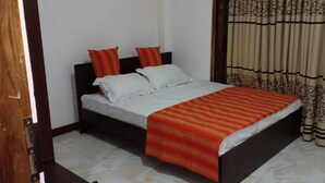 Un dormitorio con una cama, dos almohadas, una colcha a rayas y cortinas.