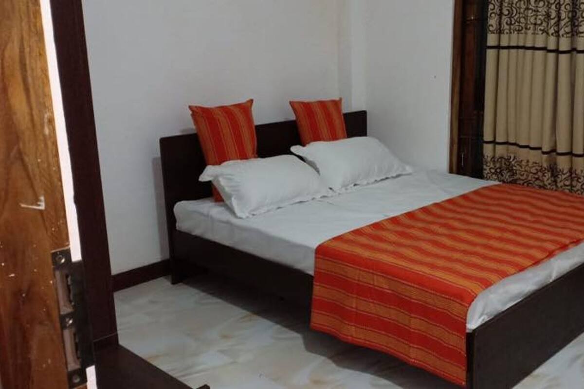 A bedroom with a bed, two pillows, a striped blanket, and curtains.