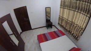 Un dormitorio con cama, espejo, armario y cortinas.