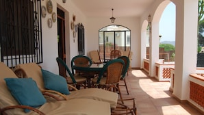 A sunlit patio with wicker furniture, a glass table, and a view of the garden. - See view villa with pool and big garden. (MORAIRA, (ALICANTE) ESPAÑA)